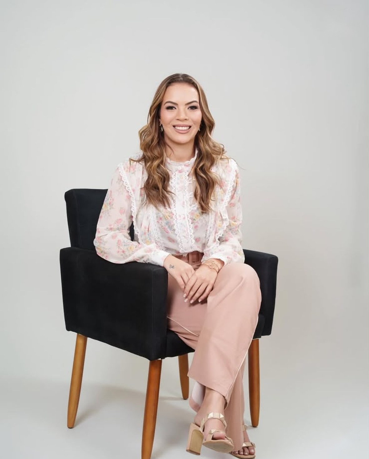Dra. Dênia Martins sentada em poltrona, sorrindo